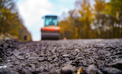Tandem vibration roller compactor working on asphalt pavement, selective focus on road repair. Focus at the asphalt