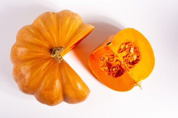 Whole fresh orange big pumpkin and slice of pumpkin on white background, closeup. Organic agricultural product, ingredients for cooking, healthy food vegan.
