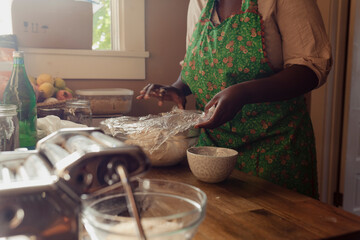 Home baker covering bread dough inside of a home kitchen