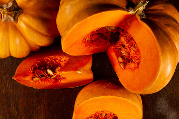 Whole fresh orange big pumpkin and slice of pumpkin on black background, closeup. Organic agricultural product, ingredients for cooking, healthy food vegan.