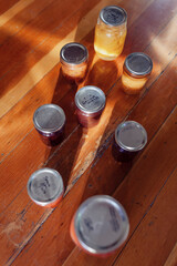 Assortment of canned jams, jellies and fruit preserves in glass jars on wood background