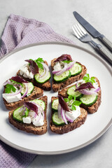 Canapes with toasted bread with sunflower and flax seeds, feta cheese, cucumber and onion