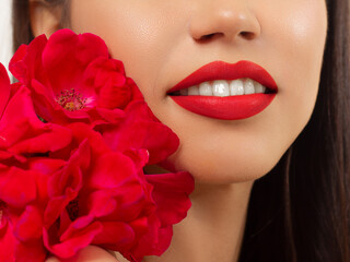 Fototapeta premium Smiling young girl. Beauty face closeup. Sexy lips. Beauty natural lip makeup detail. Beautiful make-up close-up. Sensual open mouth with teeth. Lipstick and lipgloss. Flowers