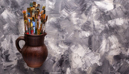 Paint brush in clay jug at  art painting canvas as abstract background. Paintbrush for painting