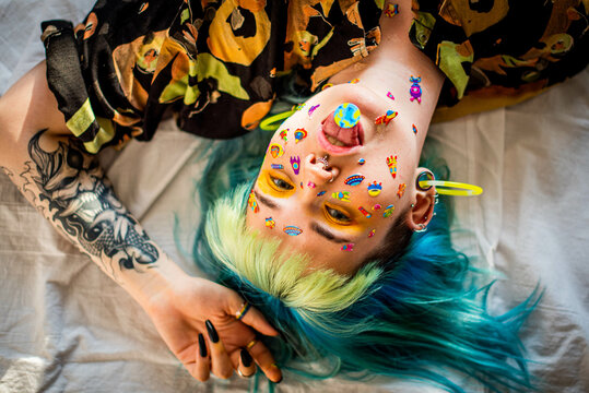 Closeup fashion portrait young pretty beautiful girl with green and blue hair. Beautiful fashion girl with luxury professional makeup and funny emoji stickers glued on the face. Young woman