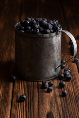 Fresh blueberries are pouring out of mug on a wooden background