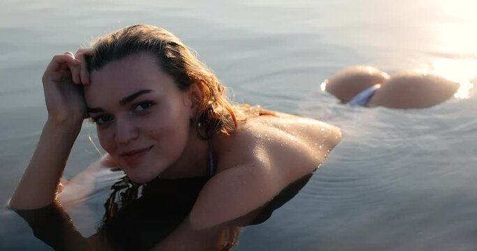 Beautiful woman lying in the lake sexy looking at camera with naked buttocks
