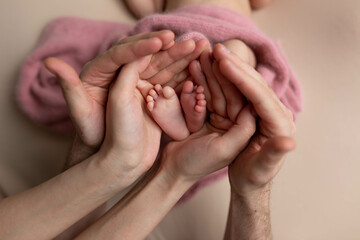 the legs of the child in the arms of the mother and the father, the legs of a newborn baby