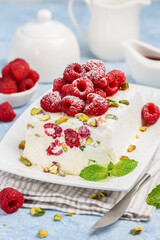 Semifreddo with raspberries and pistachios on a white platter. Traditional Italian dessert. Selective focus. 