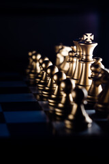 Vertical shot of golden chess pieces on a chessboard