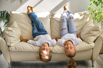 little girl and boy are lying on their backs on sofa