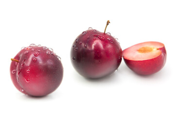 Ripe fresh organic plums whole and half in water drops isolated on white background.