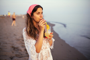 Fototapeta na wymiar Young woman drinking lemonade on beach