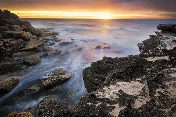 sunrise on the water and rocks on coast