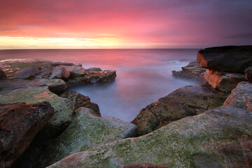 a rocky cliff with water and a mountain in the background