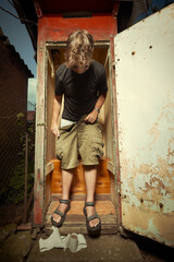 Fototapeta na wymiar Man leaving wooden toilet latrine on summer cottage