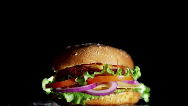 Big and tasty burger is rotating on the plate. Isolated footage