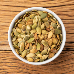 Pumpkin seeds in a bowl over wooden table