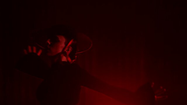Beautiful hat dressed girl dancing latin dance . Professional female dancer dancing flamenco , rumba or salsa on red background with lines . Spanish dance movements . Shot ARRI ALEXA Cinema Camera .