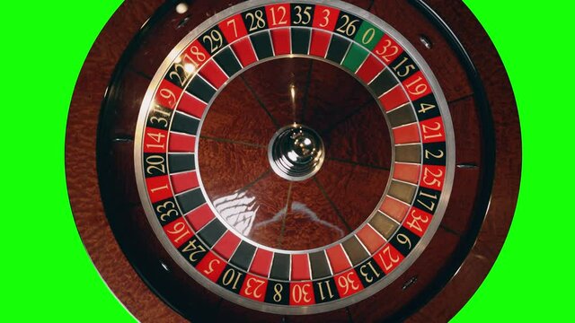 Close up of roulette wheel in motion at a green screen background. The wheel ball is spinning. Concept of casino and gambling.