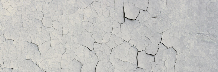 Peeling paint on the wall. Panorama of a concrete wall with old cracked flaking paint. Weathered rough painted surface with patterns of cracks and peeling. Wide panoramic texture for grunge background