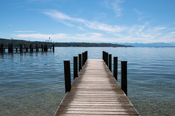 Fototapeta premium Wooden jetty projecting into Lake Starnberg in Starnberg in Bavaria, Germany, on a sunny summer day