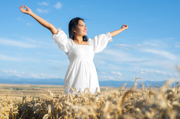 Portrait of happy young woman in a white dress, on a wheat field. Lifestyle and happiness concept. Woman with open arms . High quality photo