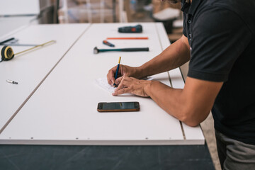 Man pointing data at a paper looking at a mobile screen in a workshop