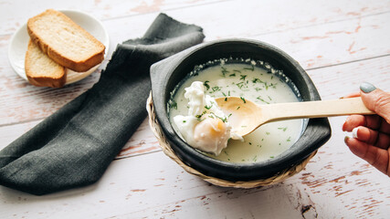 Traditional Colombian Poached Egg Soup called changua, with hand