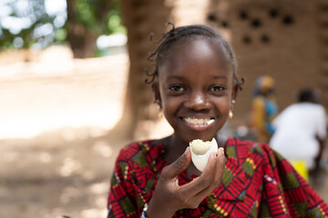 Smart black African girl eating a boiled egg with great delight