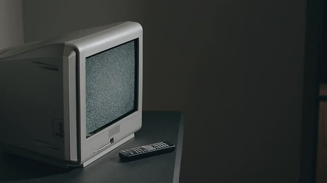 Broken Television - Old Silver TV on Black Table in Dark Room. Search for Signal. Distortion on the Screen. Close-Up, Dinamic Shot, Film Grain