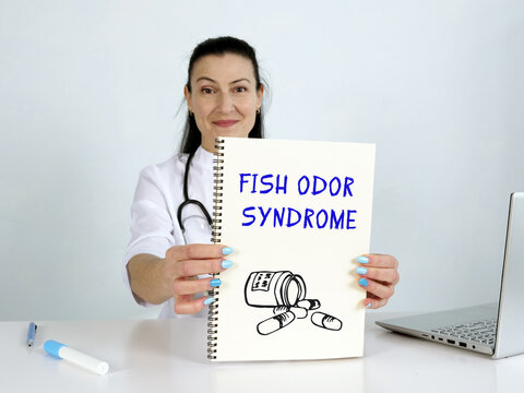  FISH ODOR SYNDROME inscription on the screen. Close up Cardiologist hands holding black laptop.