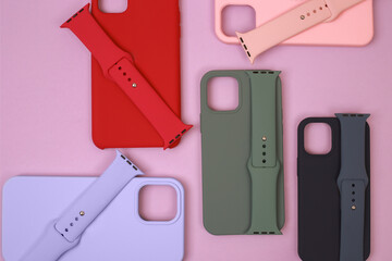 Colored silicone phone cases, complete with watch strap. Set. Up to date technology.Close up of diverse personal accessory laying on the pink background. Flat lay with copyspace