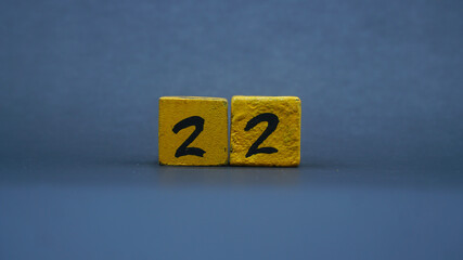 Wooden block with number 22. Yellow color on dark background