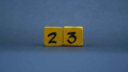 Wooden block with number 23. Yellow color on dark background