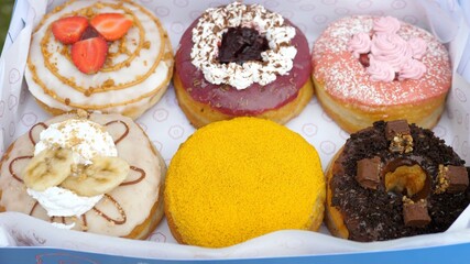 Top view of six colourful vegan doughnuts in a box