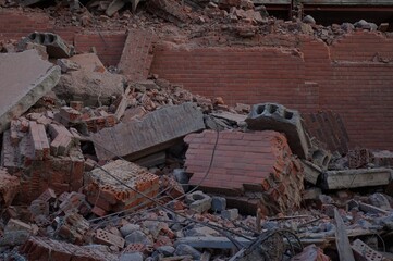 The wreckage of a new building. Demolition of the building. Piles of red brick fragments against...