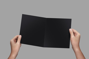 Closeup hands holding blank Bi-Fold Brochure on grey background.