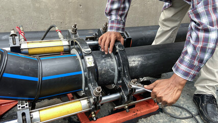 Plumber installs a hydraulic PE pipe welding machine for connecting water pipes in the factory.