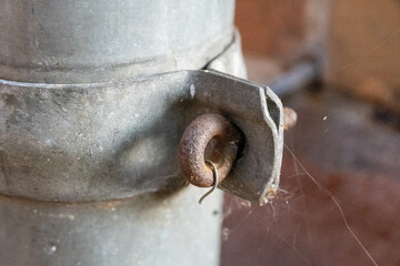Closeup of a rusty metal link on an old pipe in a factory with spiderwebs all over it