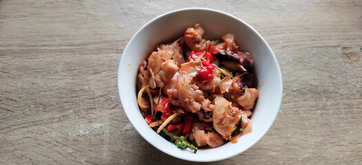 Stir fried squid in a white bowl on a wooden table