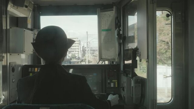 View Behind A Female Conductor At The Crew Compartment Driving Passenger Train In The City Of Sendai In Japan. medium shot