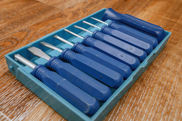 Naklejka premium set of small screwdrivers in a plastic box on a wooden background