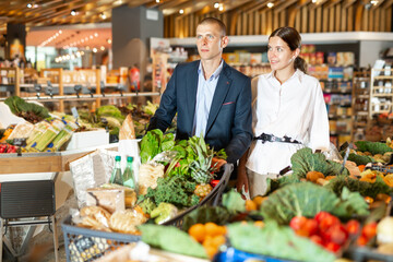 Portrait of a confident young couple wiith a shopping cart, who came to the supermarket for...