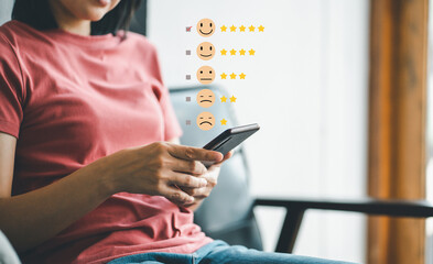Woman using smartphone pressing the happy face to Customer experience services rating concept. - obrazy, fototapety, plakaty
