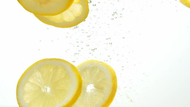 Fresh lemon dropped into water with rising air bubbles, close up view