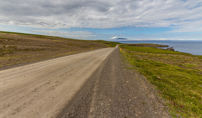 Fototapeta na wymiar Straight gravel road across icelandic meadows near shore