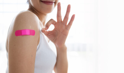 Woman holding down her shirt sleeve and showing her arm with bandage after getting vaccinated, Patients wearing masks to be vaccinated against covid-19 or corona virus, Healthy and vaccine concept