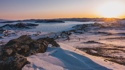 The sun has risen over a mountain range in Siberia. Reflections on the ice of a frozen lake. The...