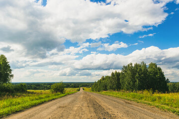 Summer countryside nature landscape. Blue sky white clouds green meadows rural road. Horizontal frame